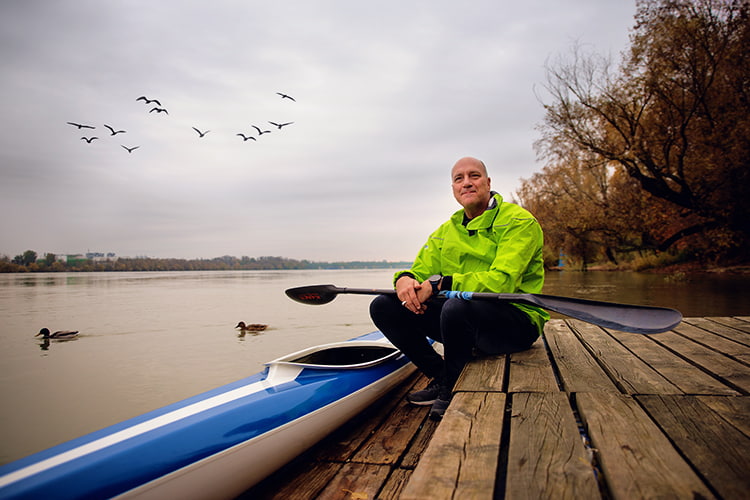 Retirement planning image of a person in a yellow jacket beside a kayak