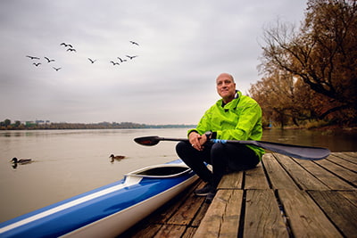 Retirement planning image of a person in a yellow jacket beside a kayak