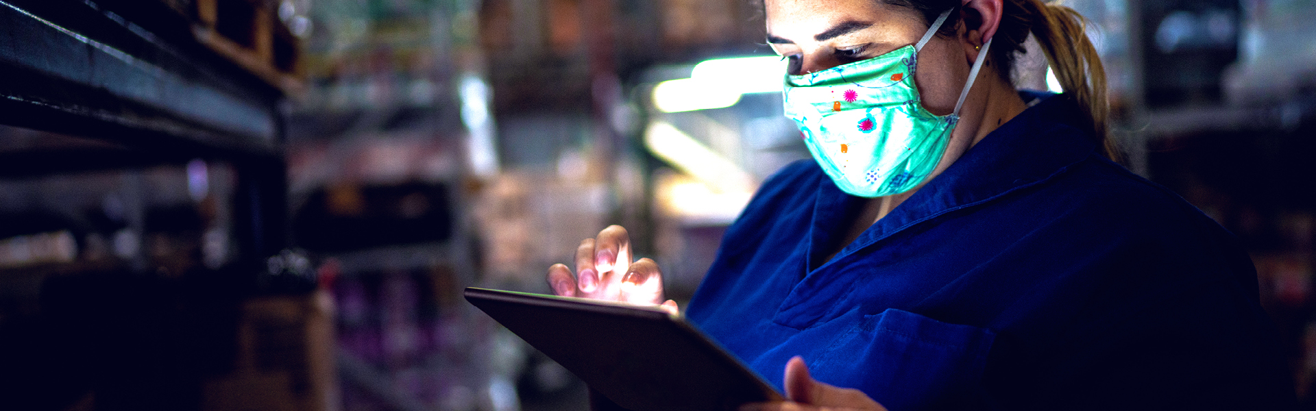 Person in a mask interacting with a tablet