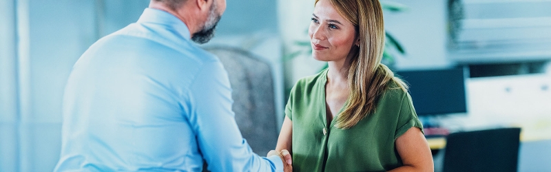 Woman and man shaking hands in business setting